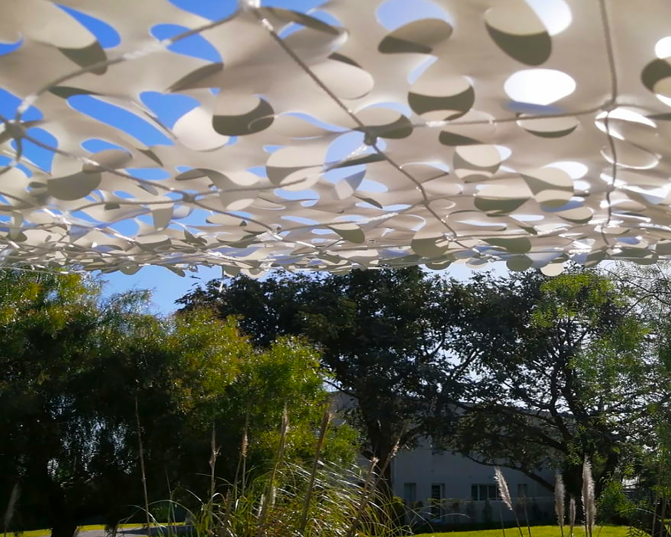 Red de camuflaje Overarg generando sombras en jardín moderno